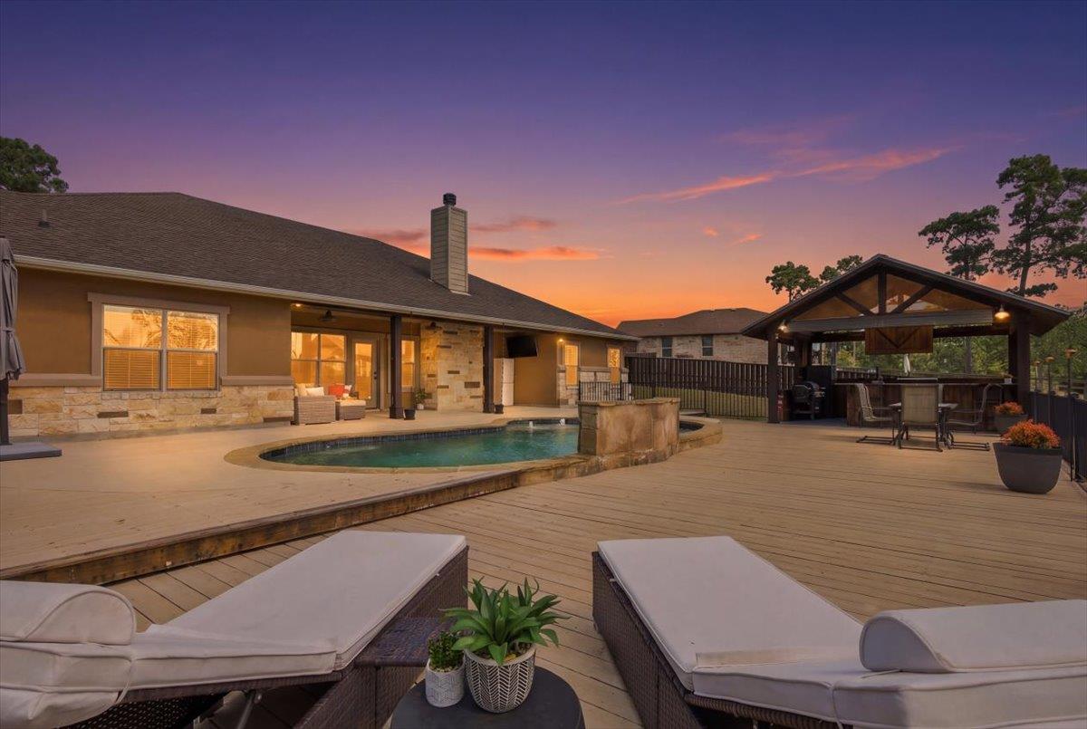An expansive wooden deck surrounds the in-ground 