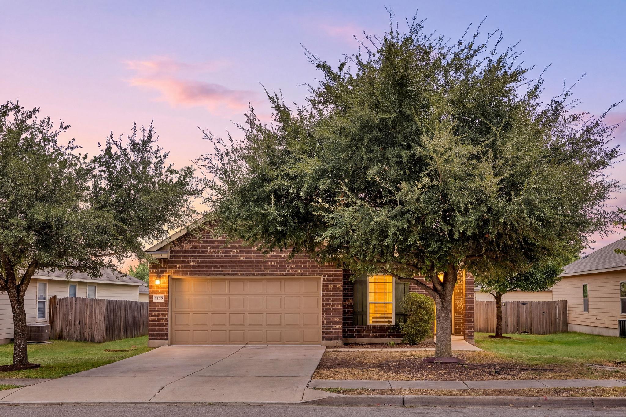 Mature trees frame the classic brick exterior and
