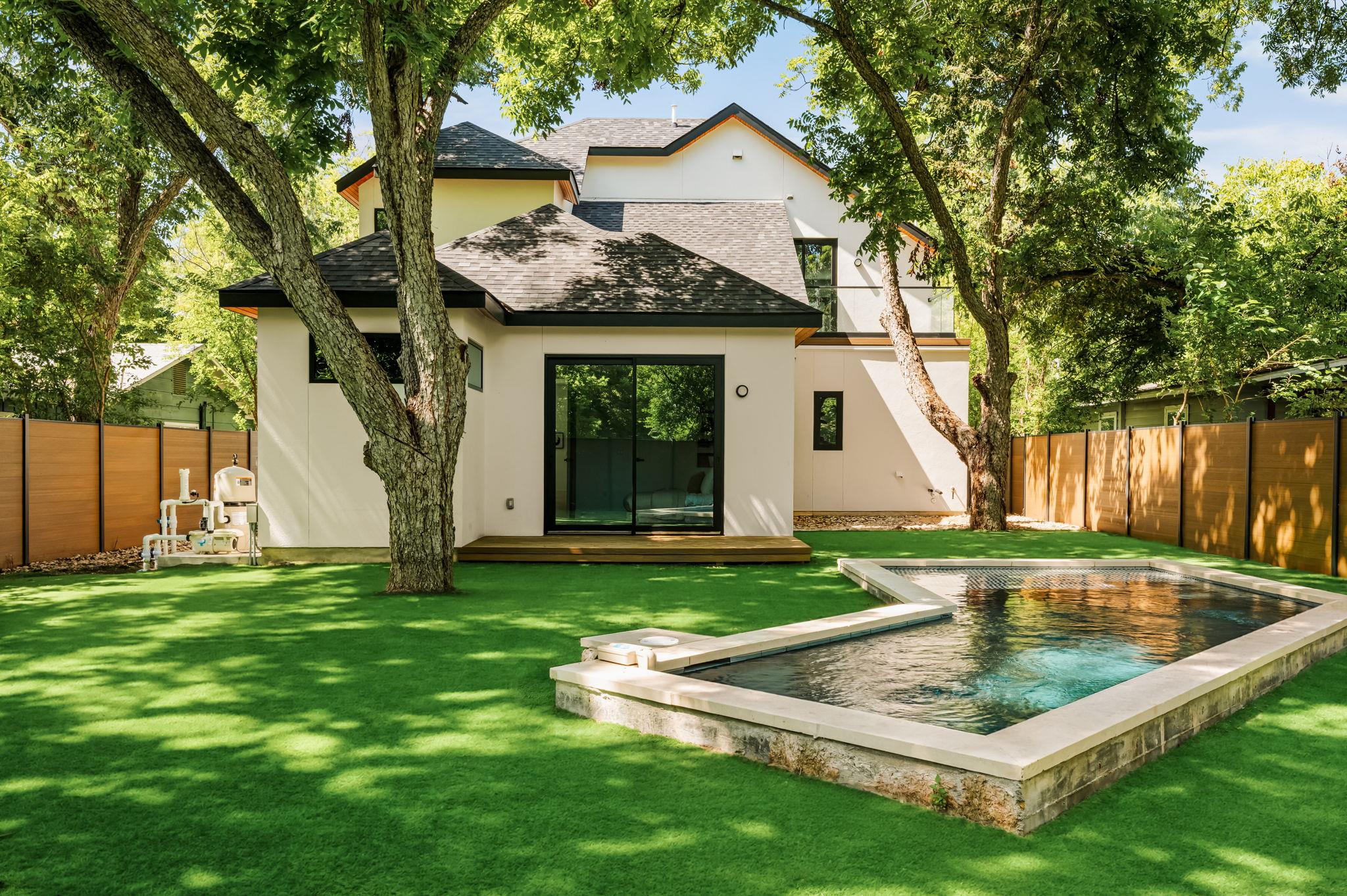 A private backyard oasis features lush green turf