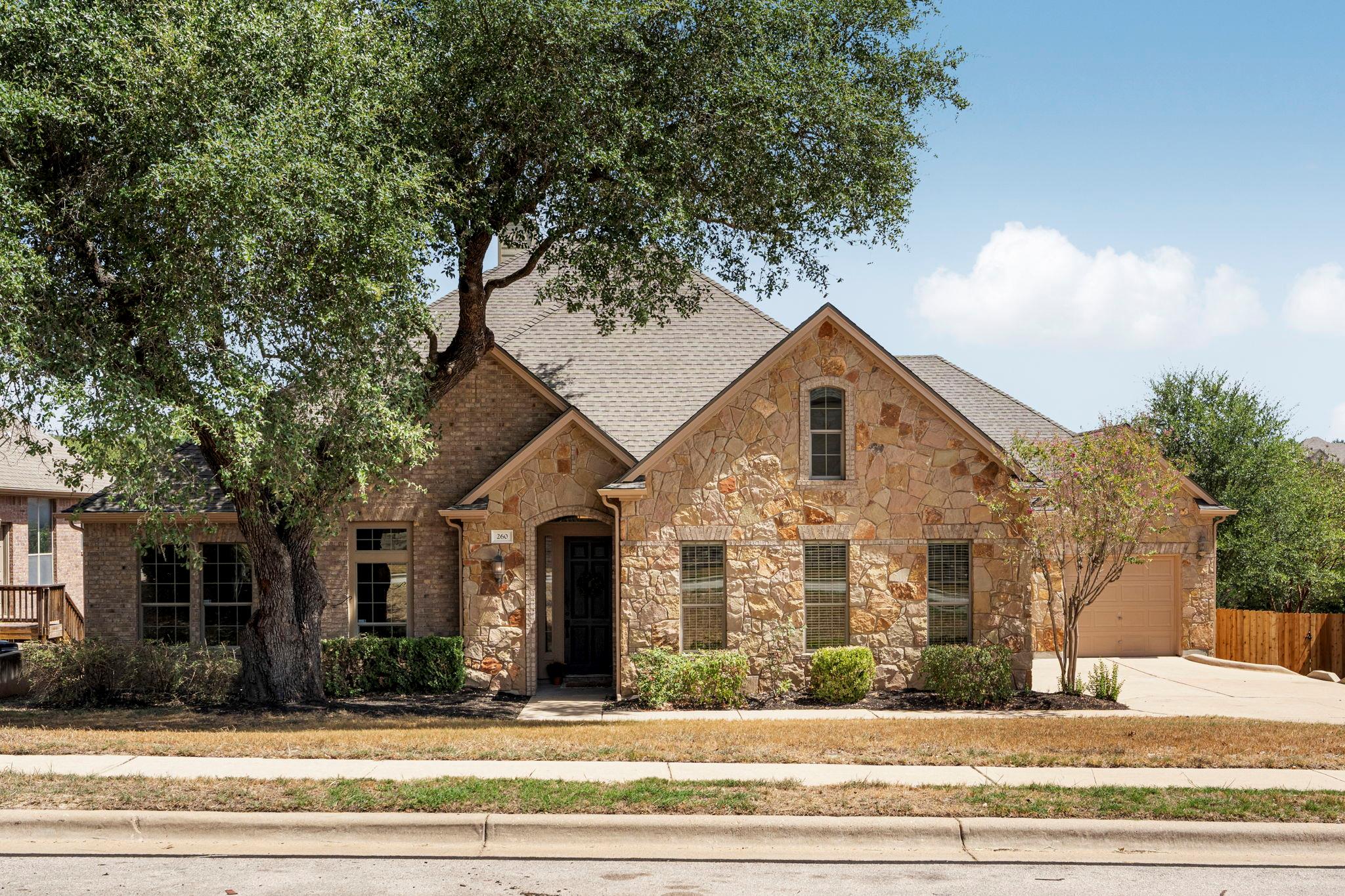 Mature trees shade a classic stone exterior with 