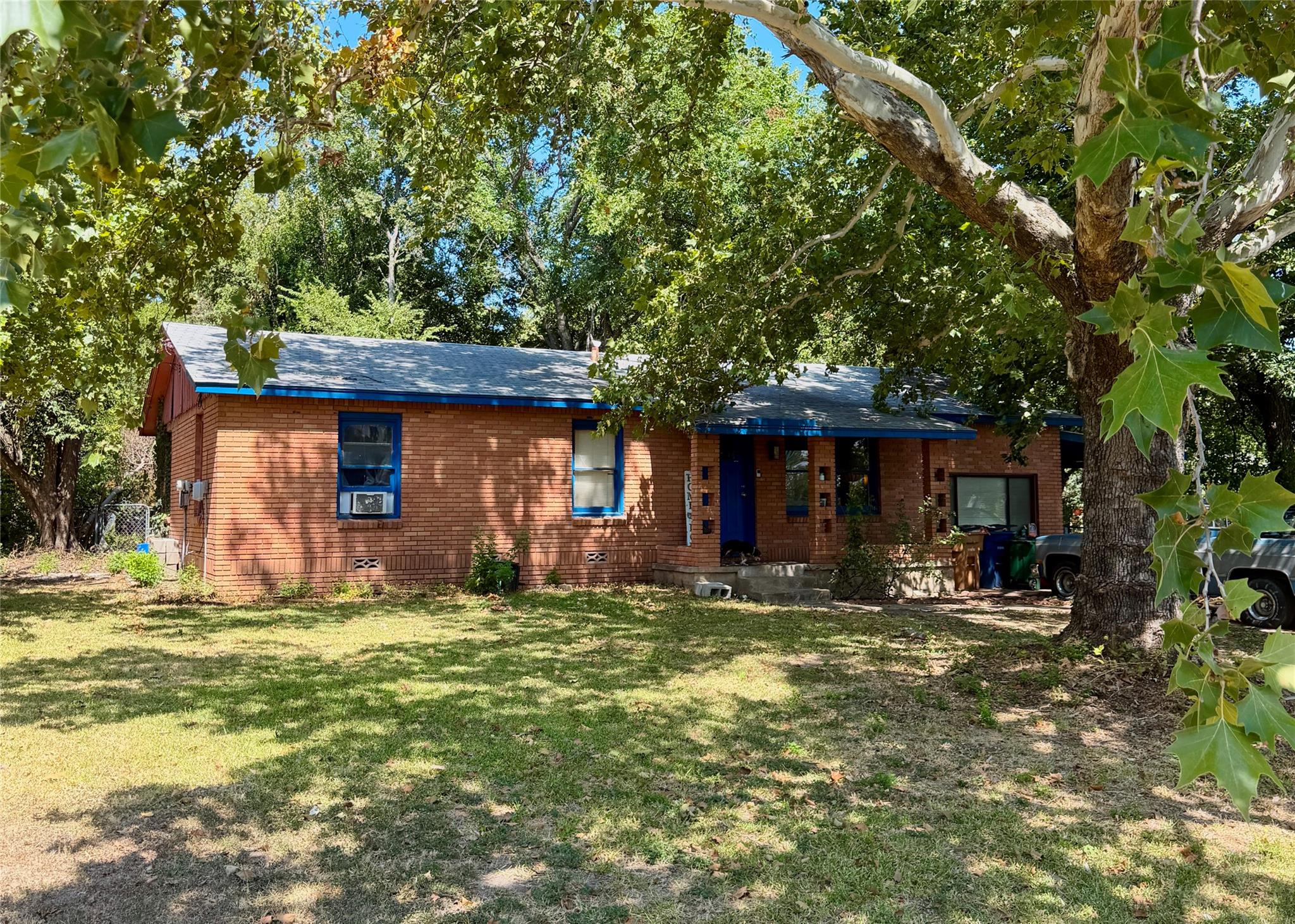 Mature trees shade a classic brick ranch home fea
