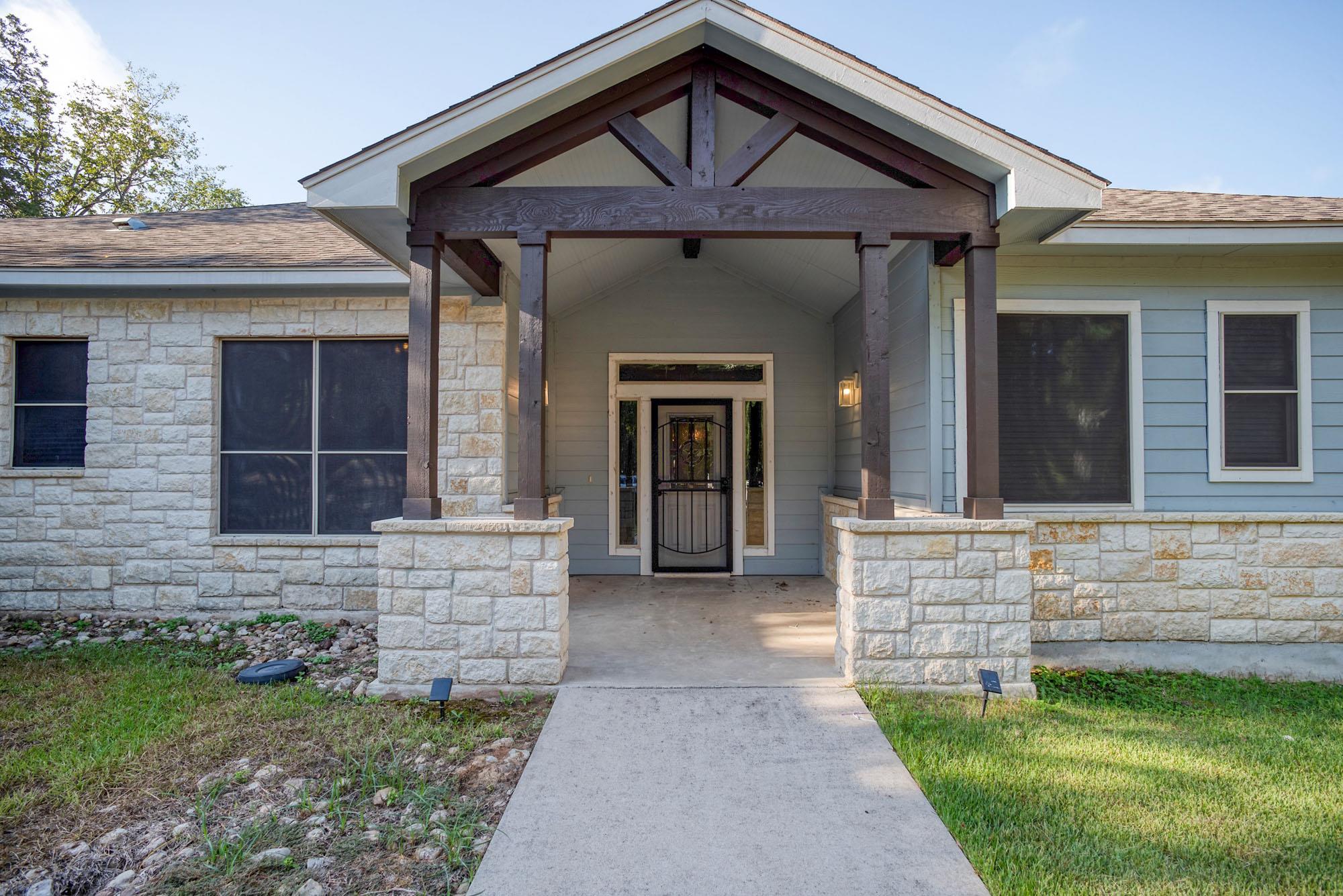 A concrete walkway leads to the covered front ent