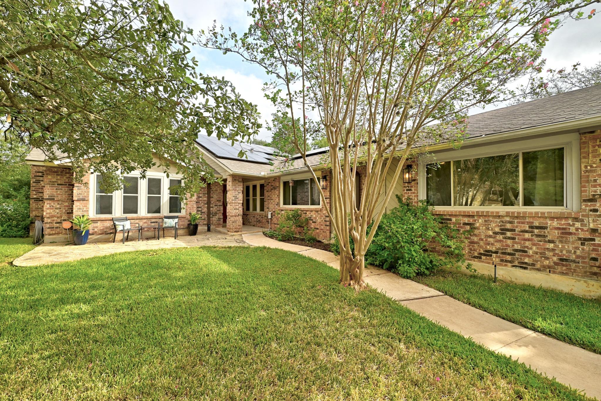 Mature trees frame a charming brick exterior with