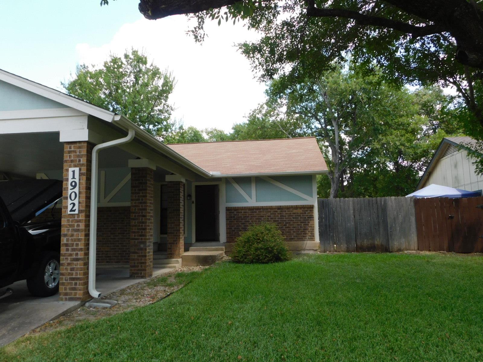 Mature trees shade a neat front lawn and a classi