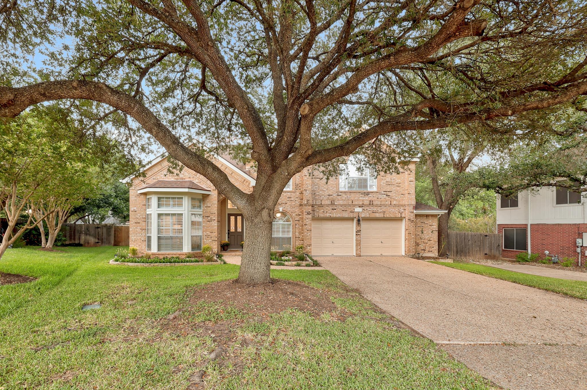 Mature shade trees frame a brick exterior with a 