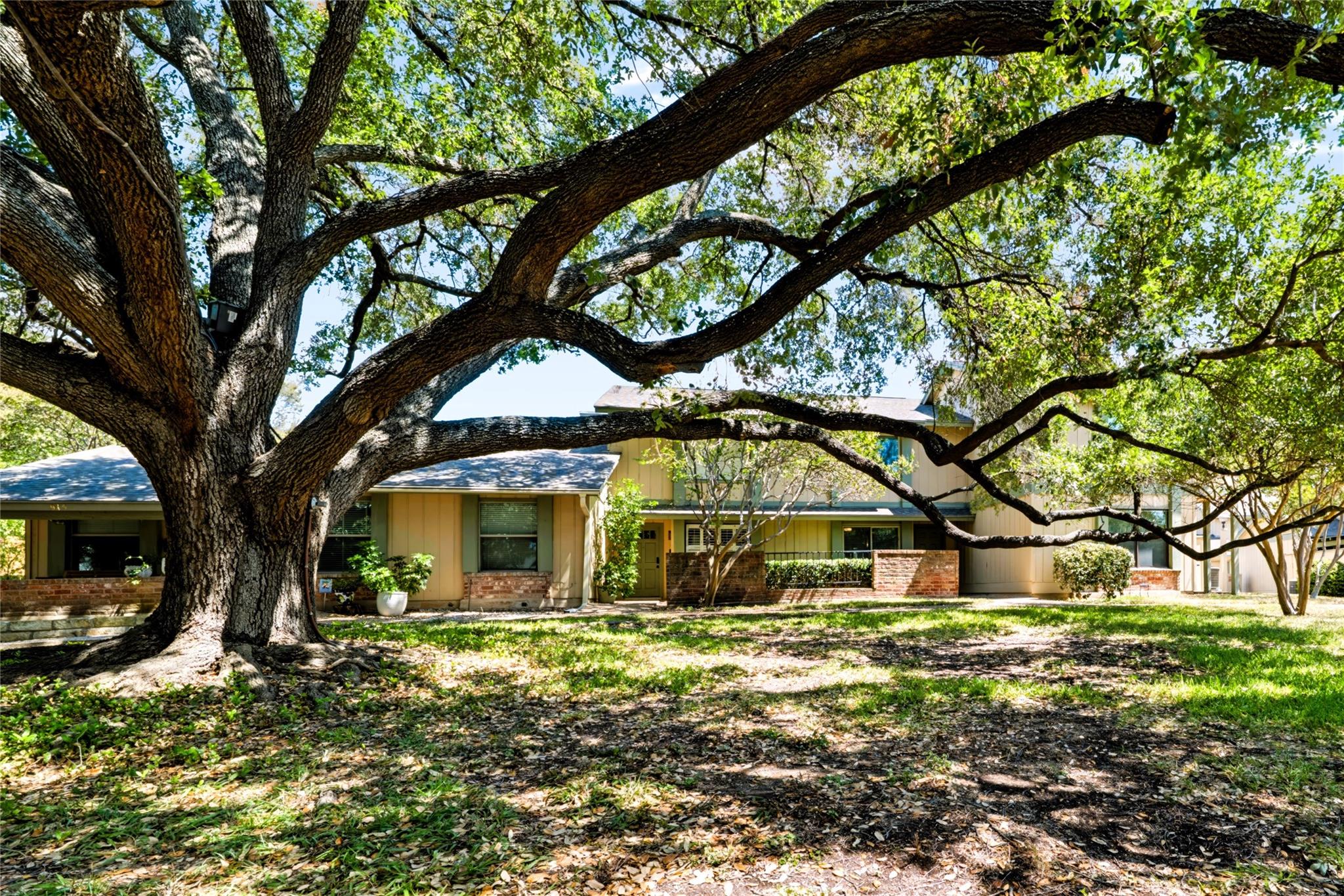 Mature oak trees frame the exterior of this multi