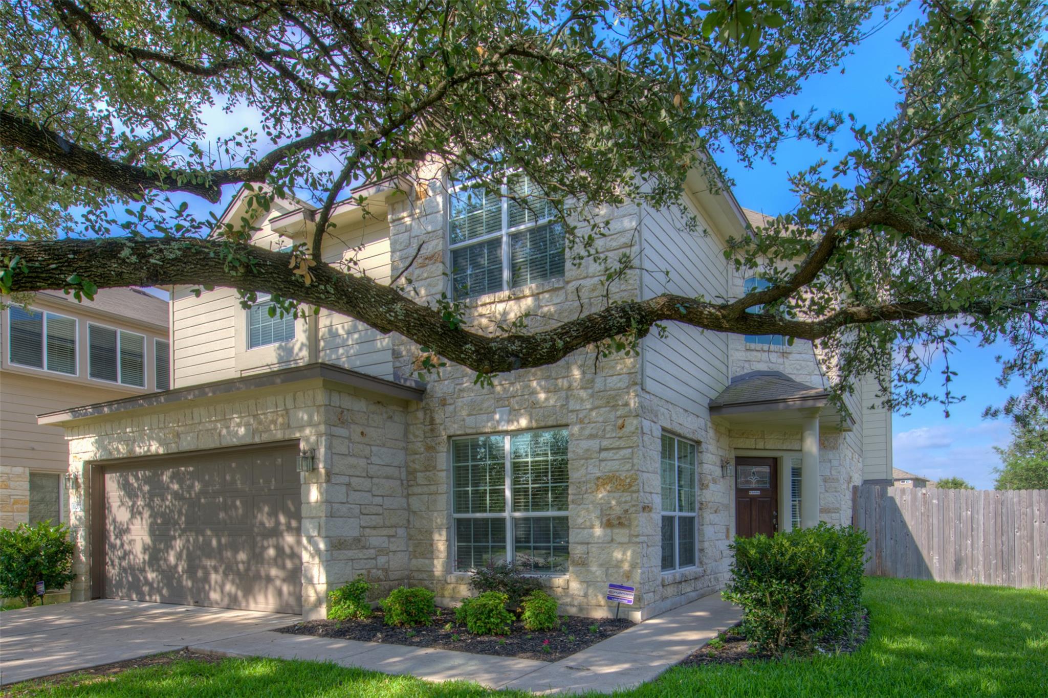 Mature shade trees frame a handsome stone and sid