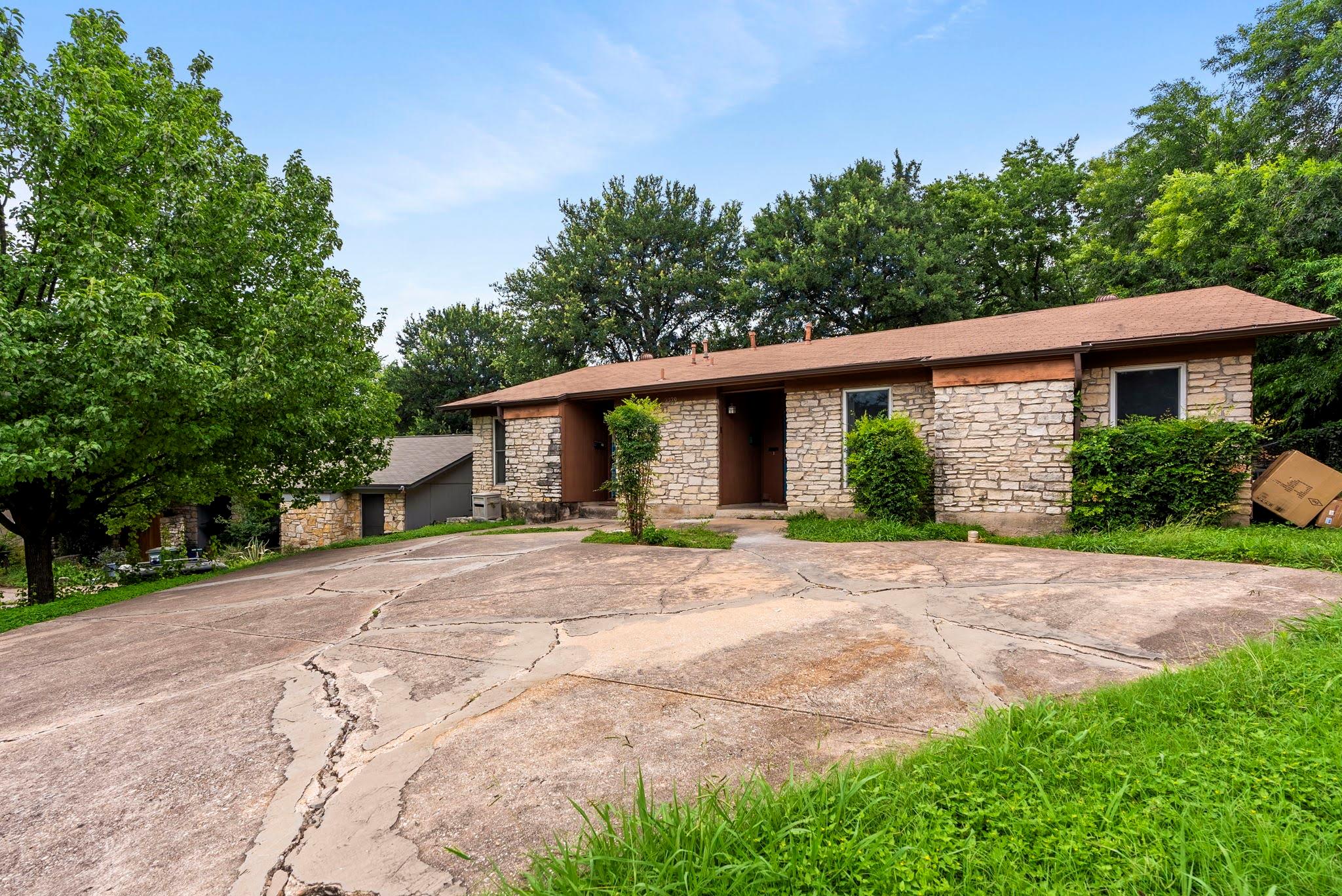 Mature trees frame a classic stone exterior with 
