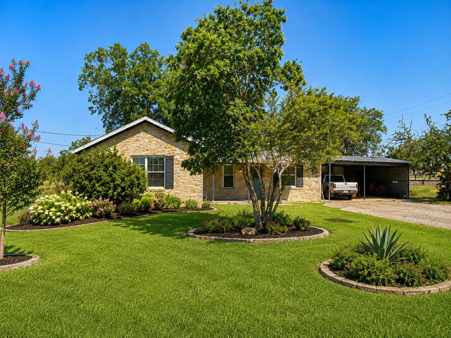 Mature trees and neat stone landscaping accent th