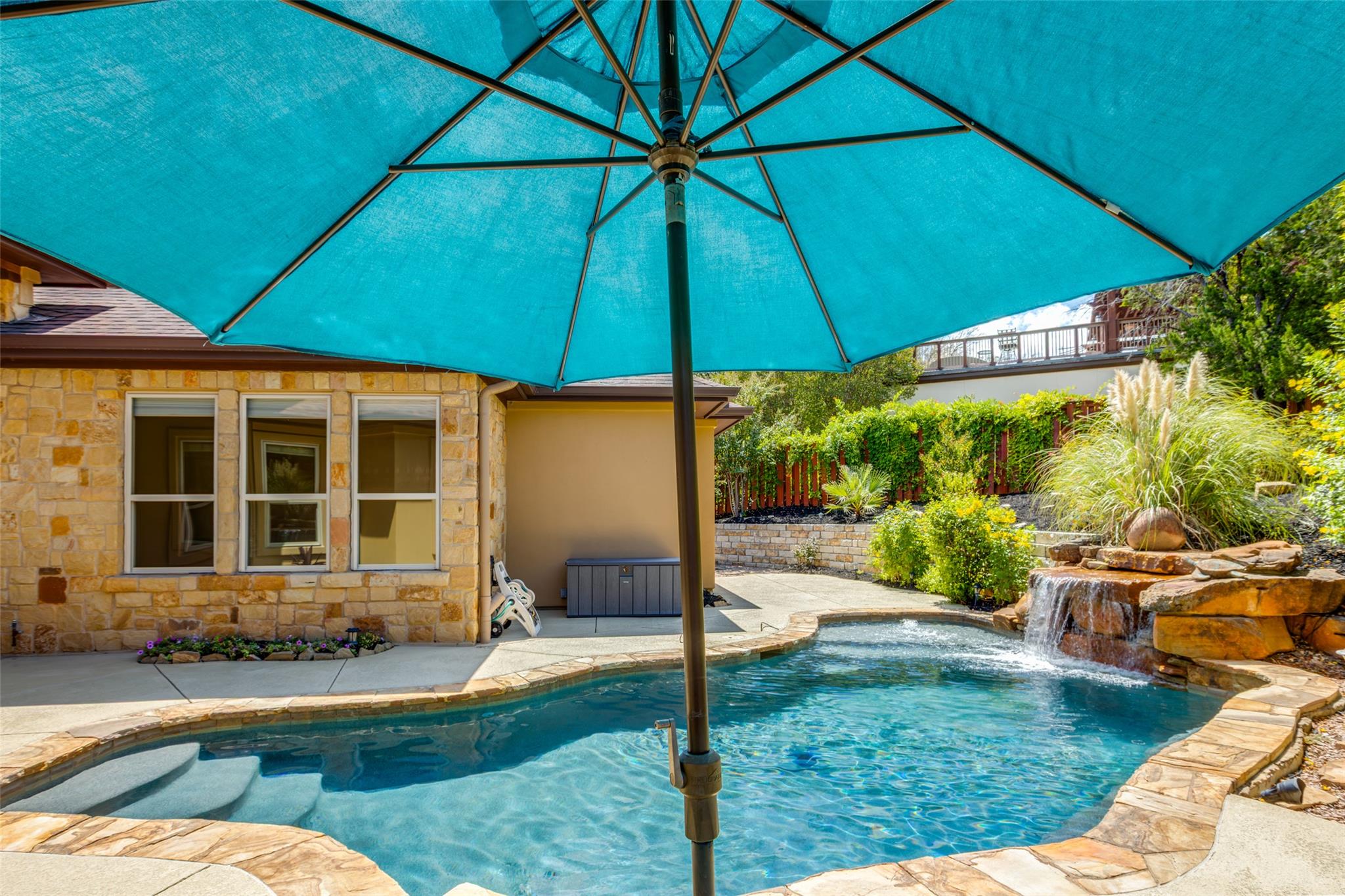 An inviting stone-bordered pool features a flowin