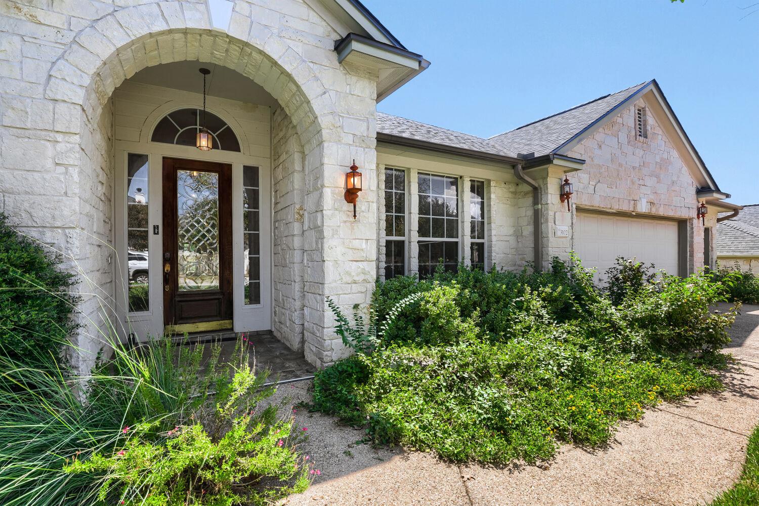An arched stone entryway leads to a classic front