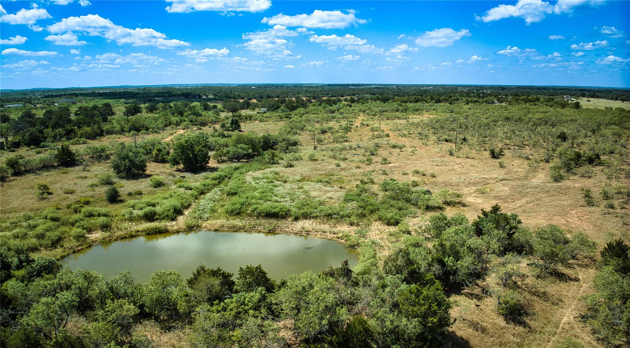 Rolling green acreage surrounds a quiet pond unde