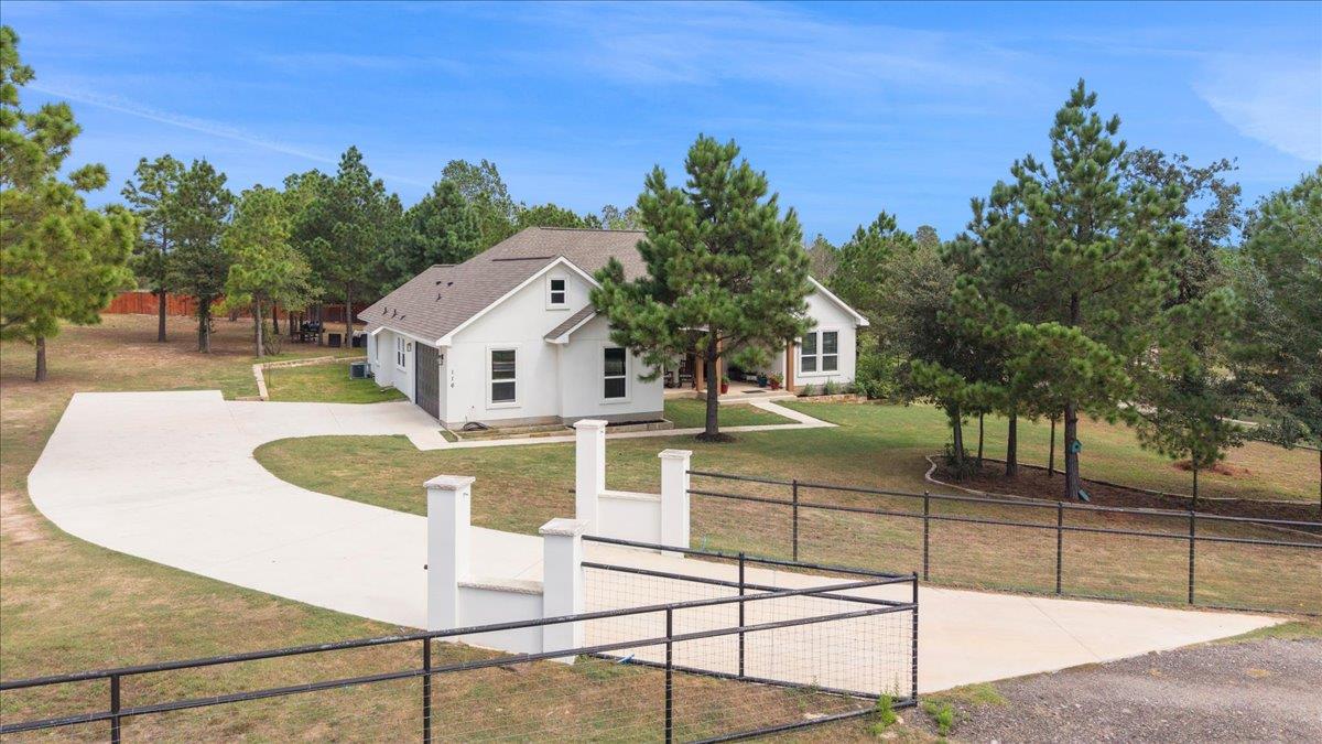 Mature trees frame a winding concrete driveway le