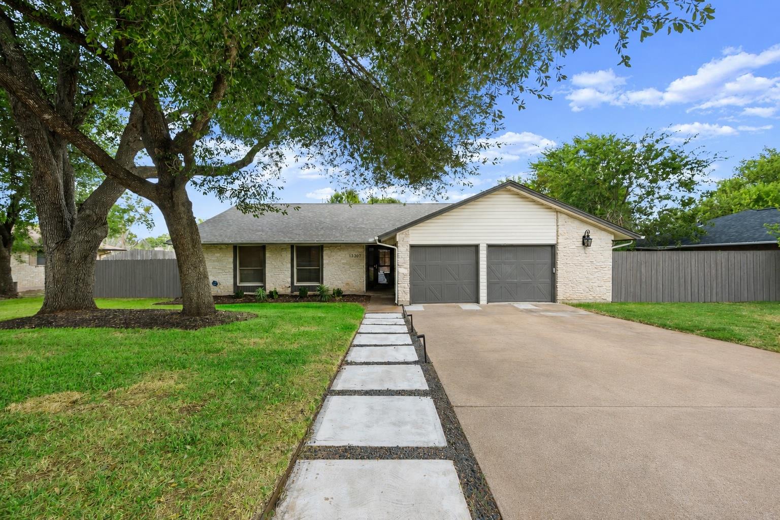 Mature shade trees and a concrete driveway lead t