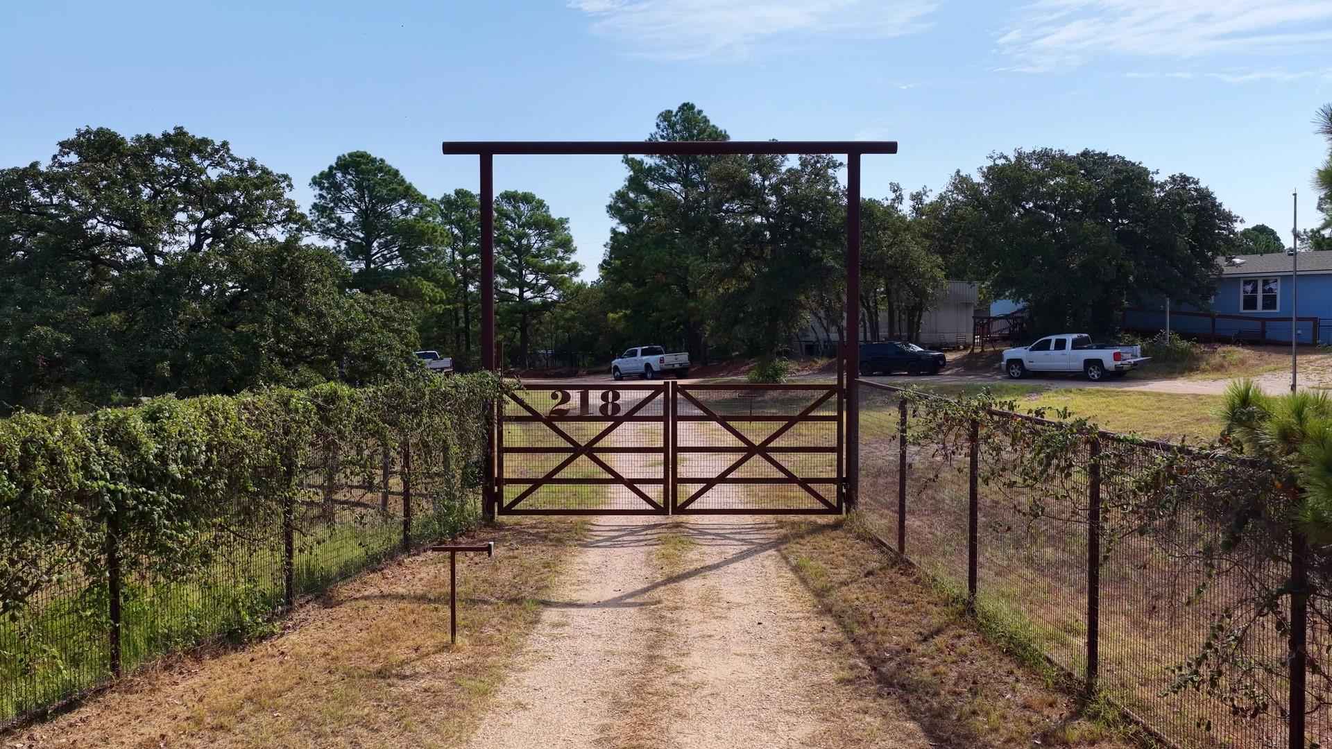 A metal gated entry secures the rustic gravel dri