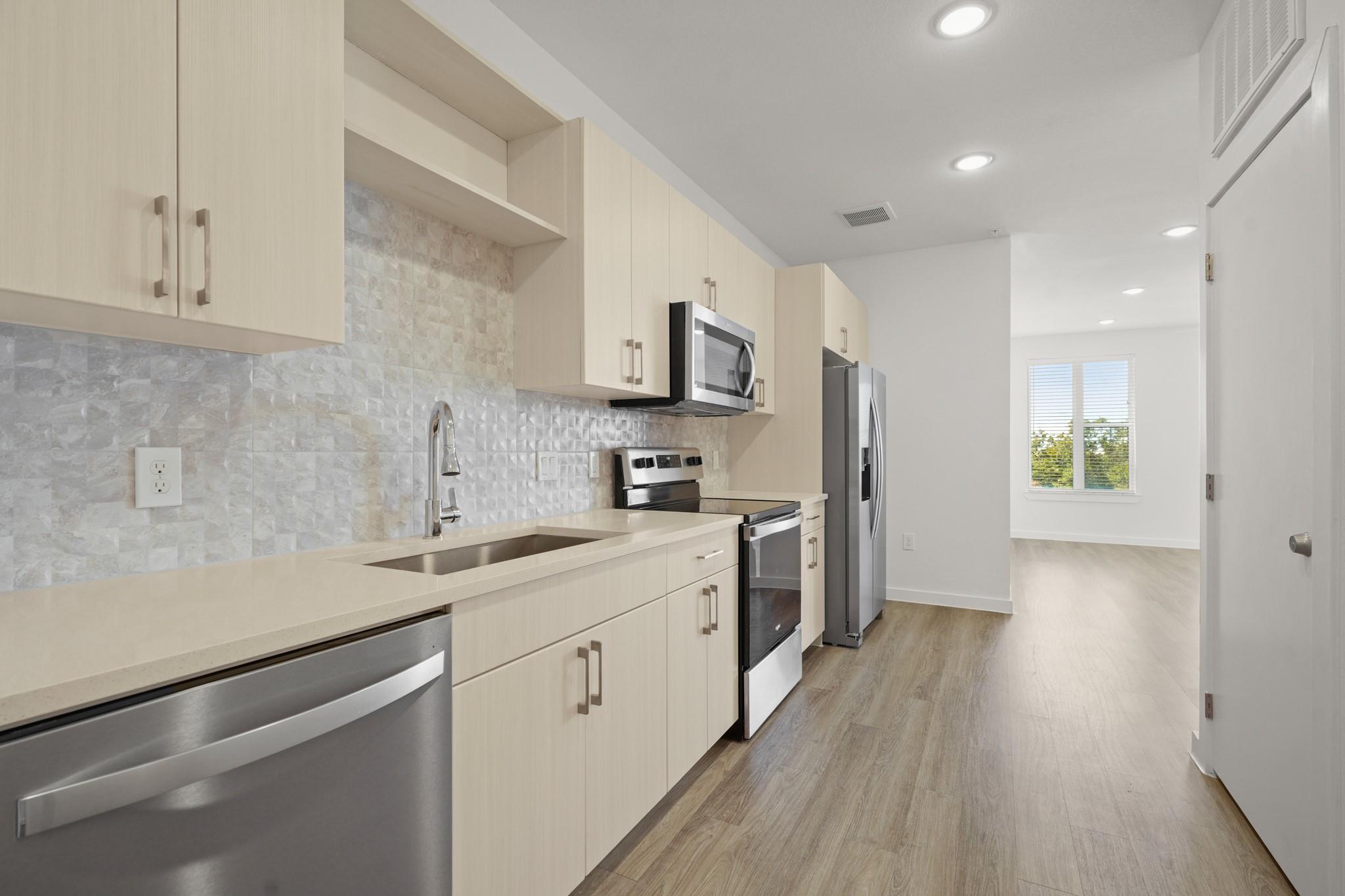 A modern galley kitchen flows into an open living