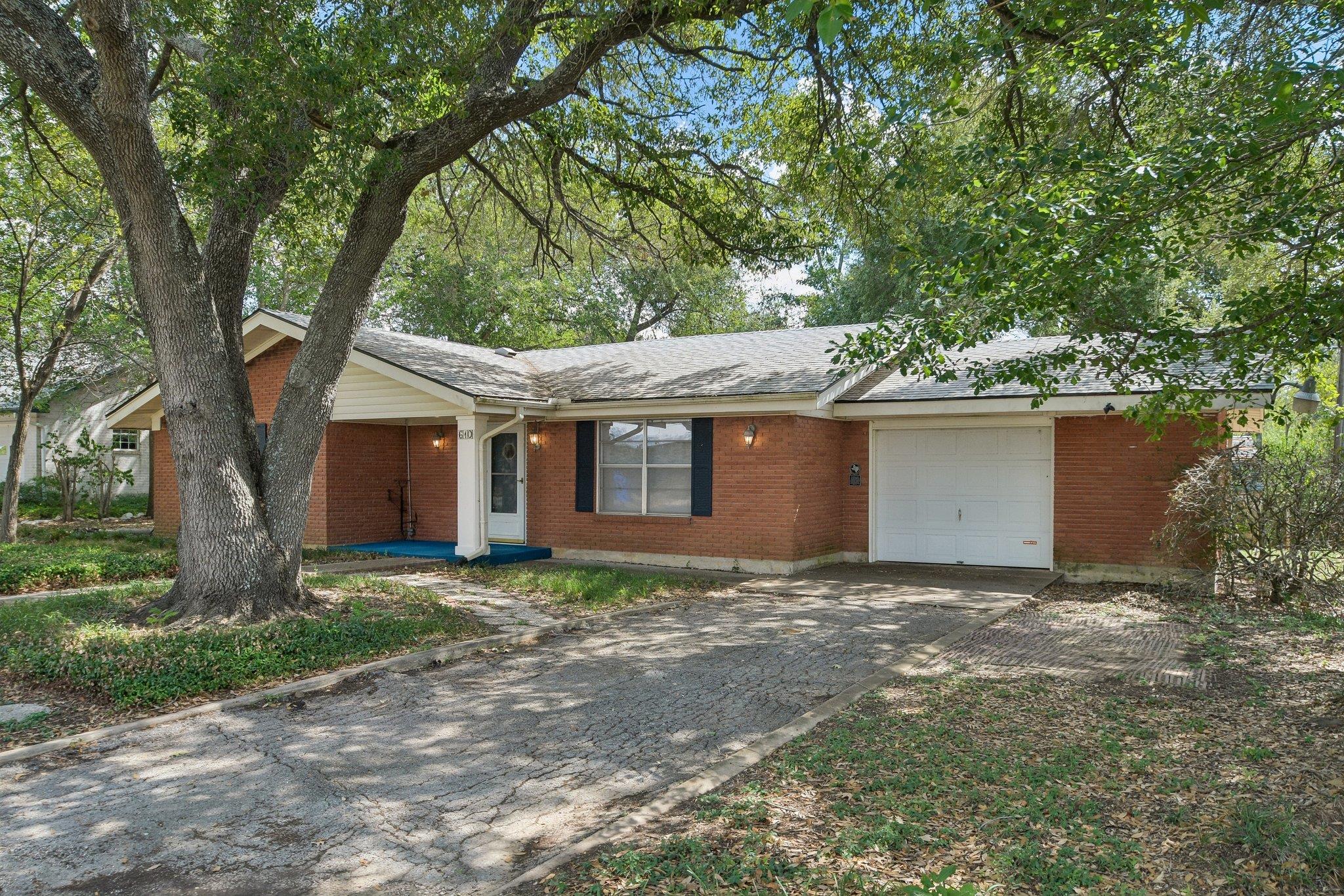 Mature trees shade a classic brick exterior compl