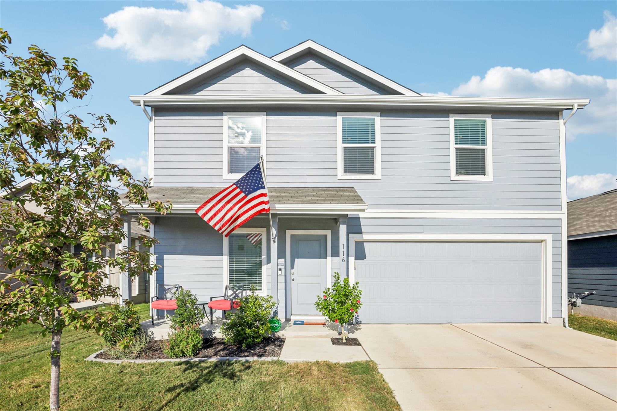 A welcoming front porch and two-car garage define