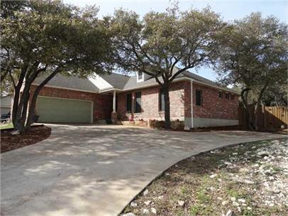 Mature trees shade a concrete driveway leading to