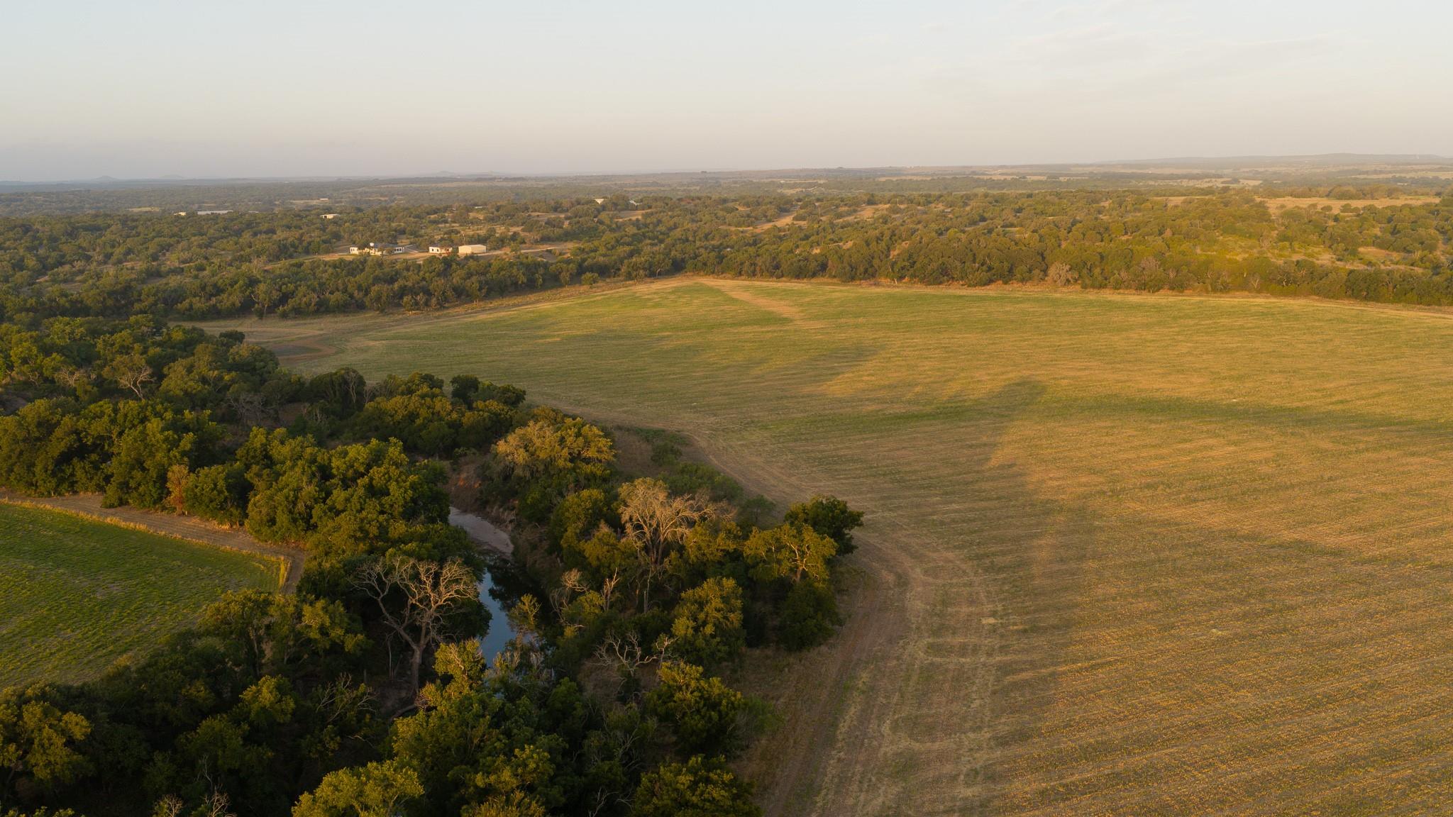 A tranquil creek meanders along the edge of open 