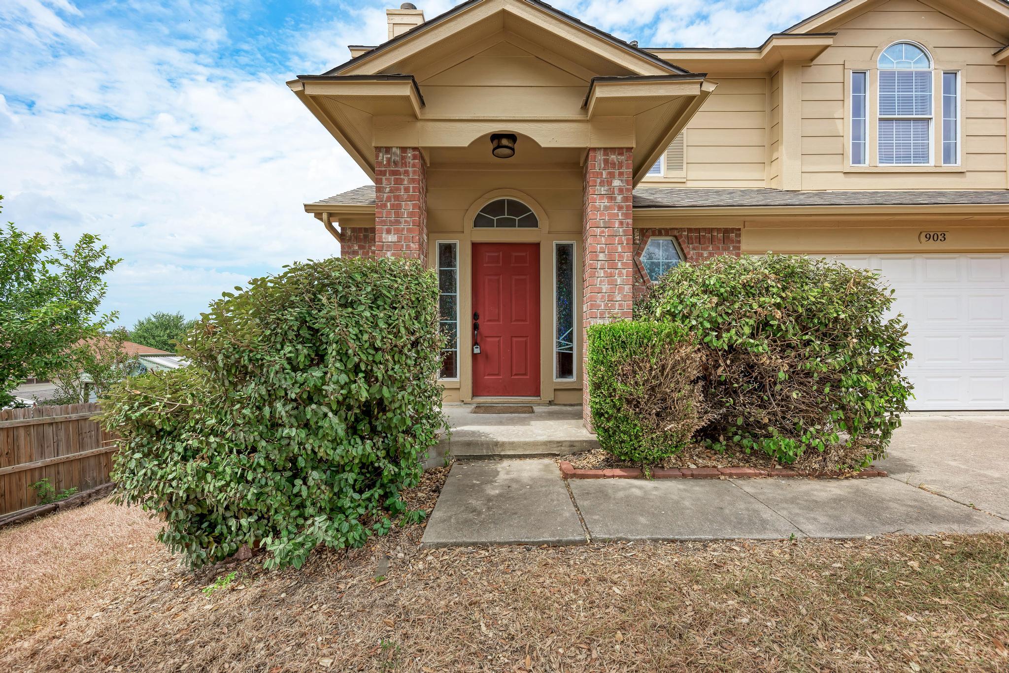 Brick pillars frame the covered entry of this cla