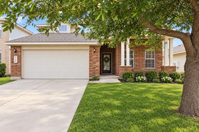 Mature shade trees and a concrete driveway lead t