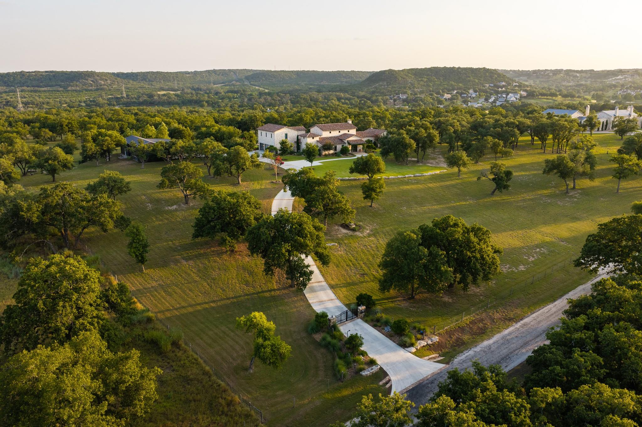A long paved driveway winds through rolling green