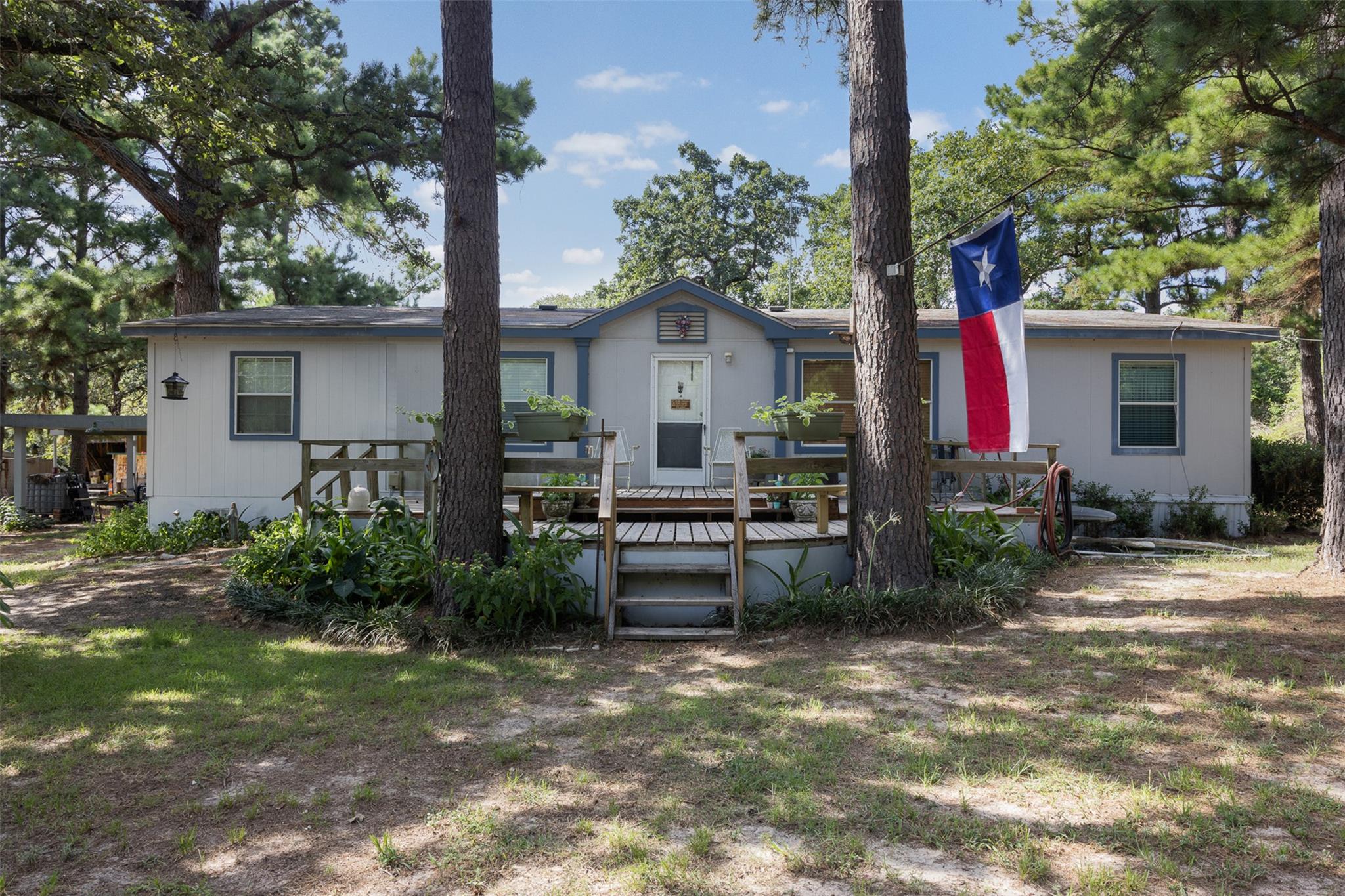 Mature trees frame the welcoming wooden deck of t