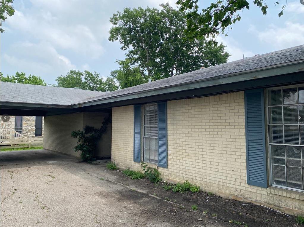 An asphalt driveway leads to a covered carport be