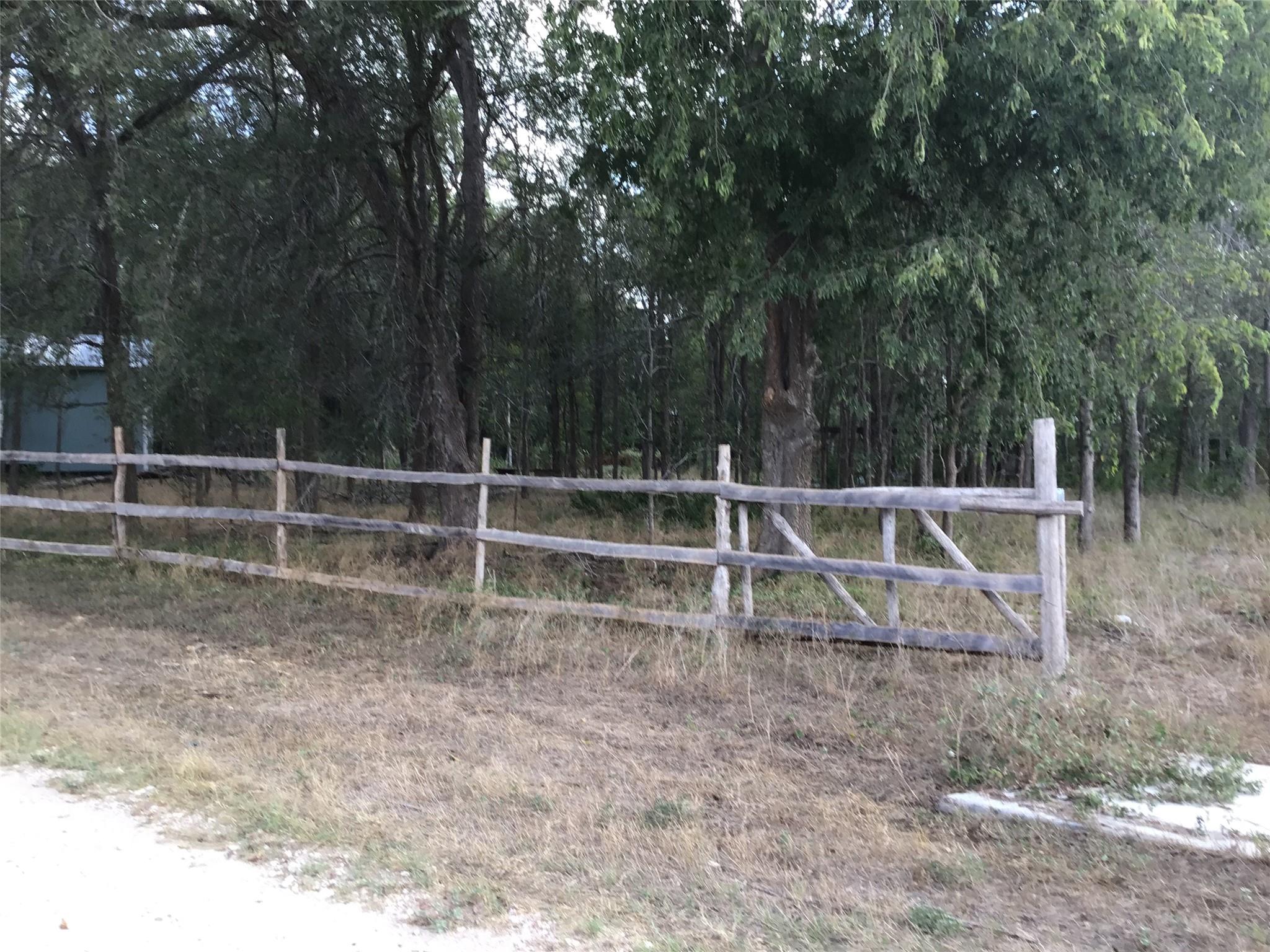 Mature trees frame a rustic wooden fence along th