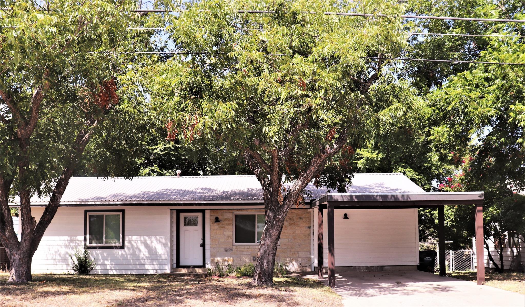 Mature trees shade a classic single-story home fe