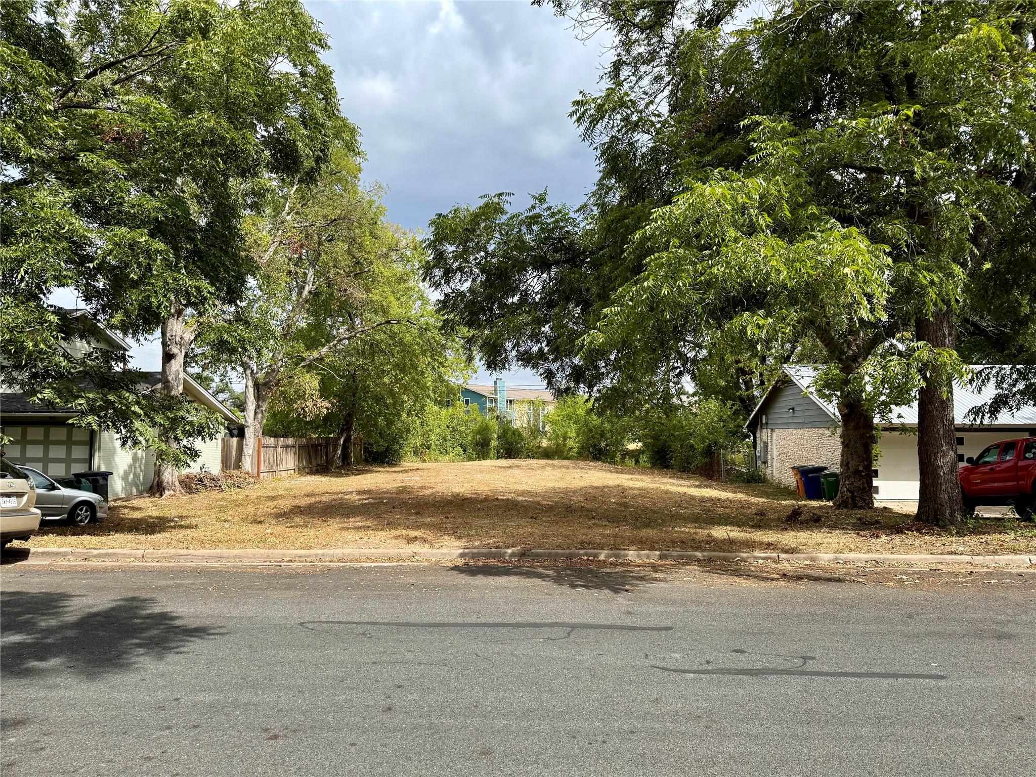 Mature trees frame a vacant residential lot ready