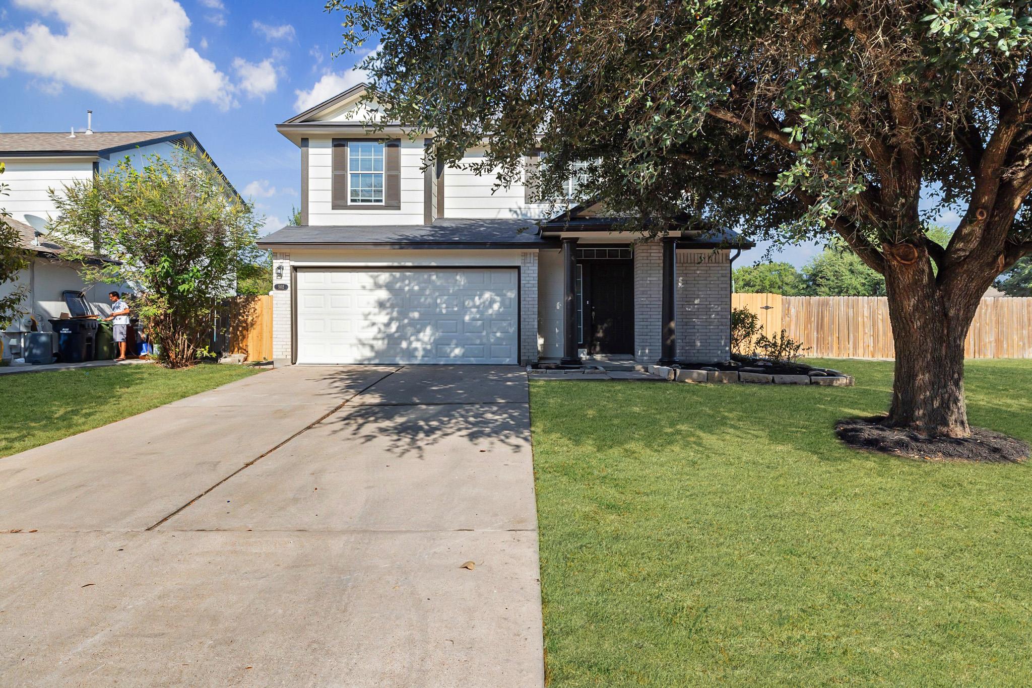 A long concrete driveway leads to the two-story h