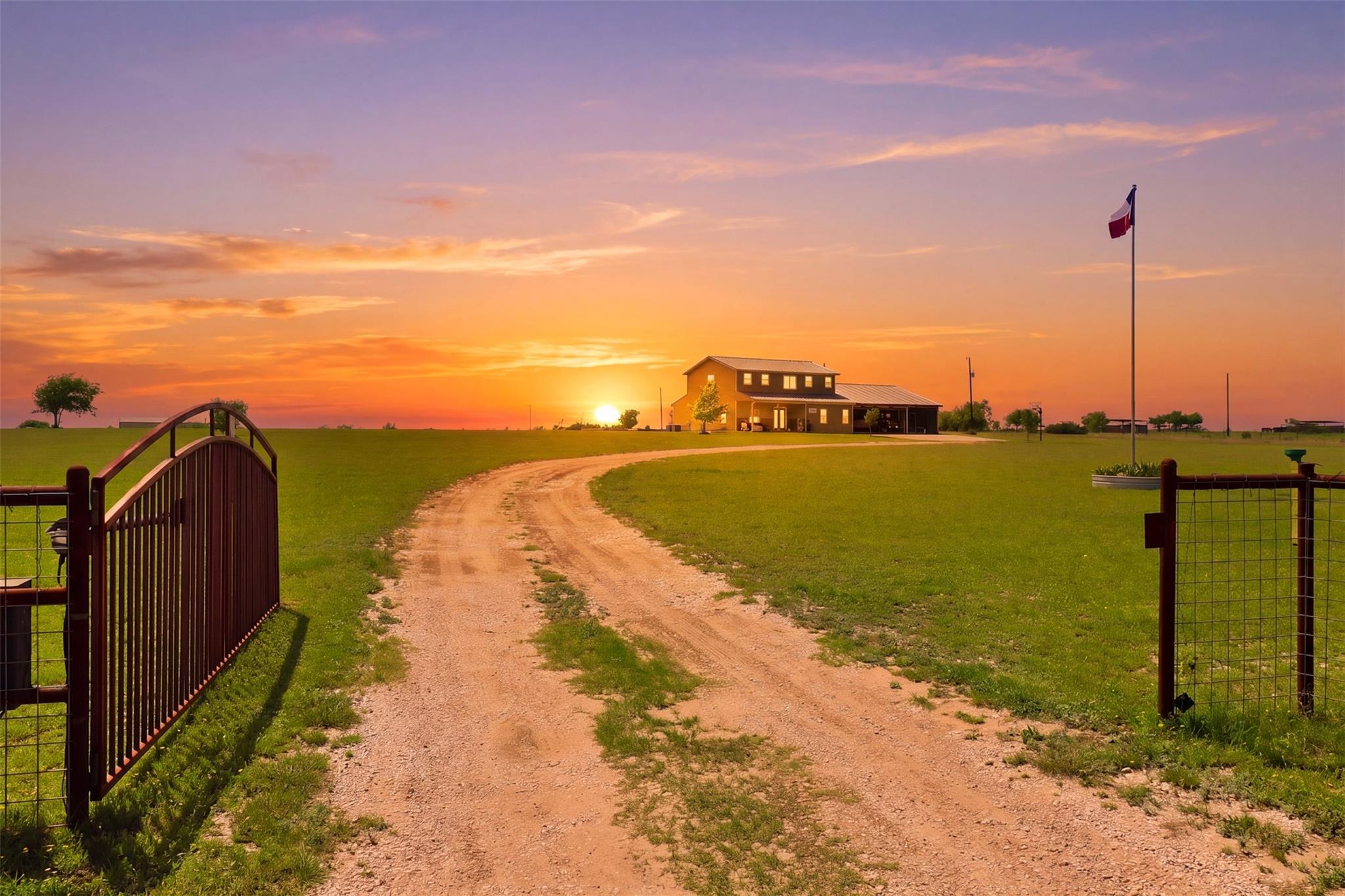 A long private driveway winds past open green pas