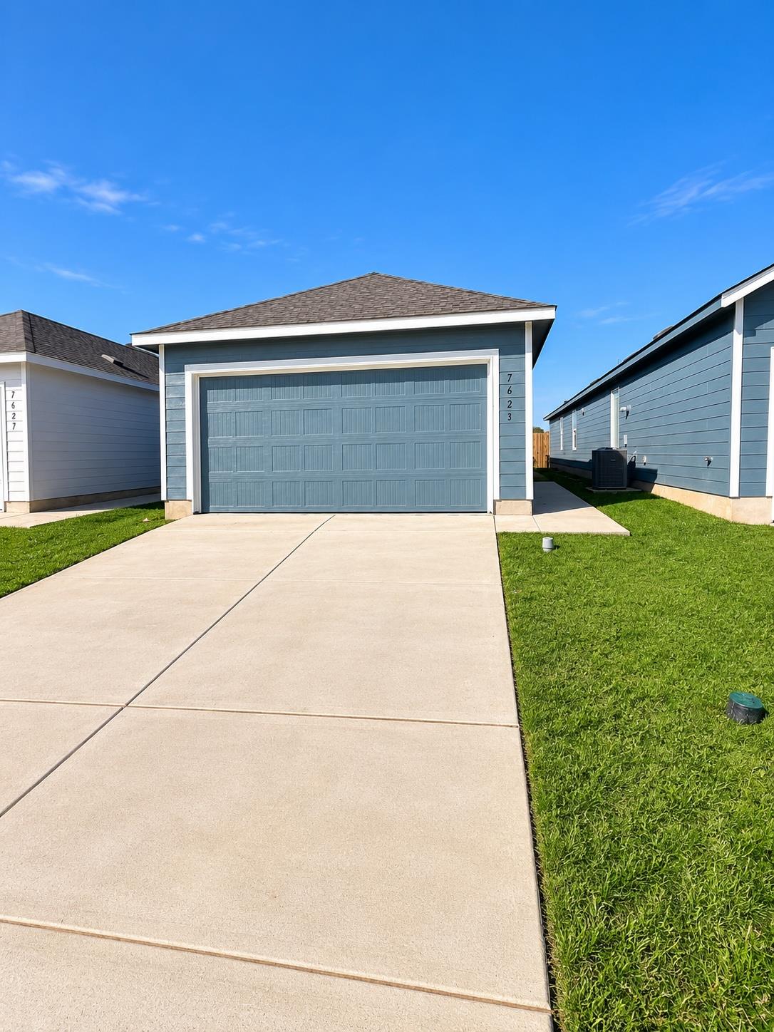 A wide concrete driveway leads straight to the de