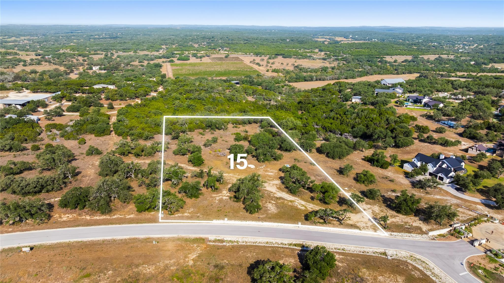 A spacious vacant lot sits nestled among mature t