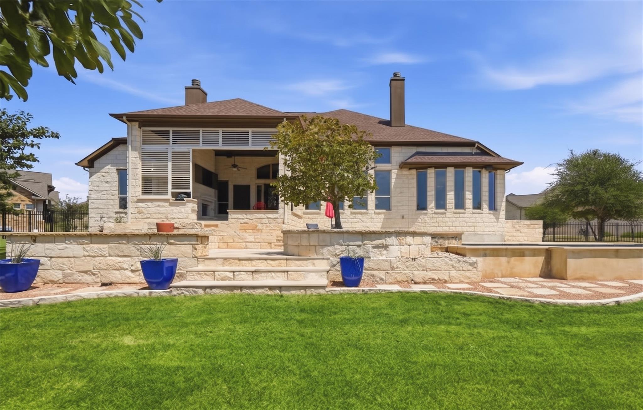 Multi-level stone patios step down to a lush lawn