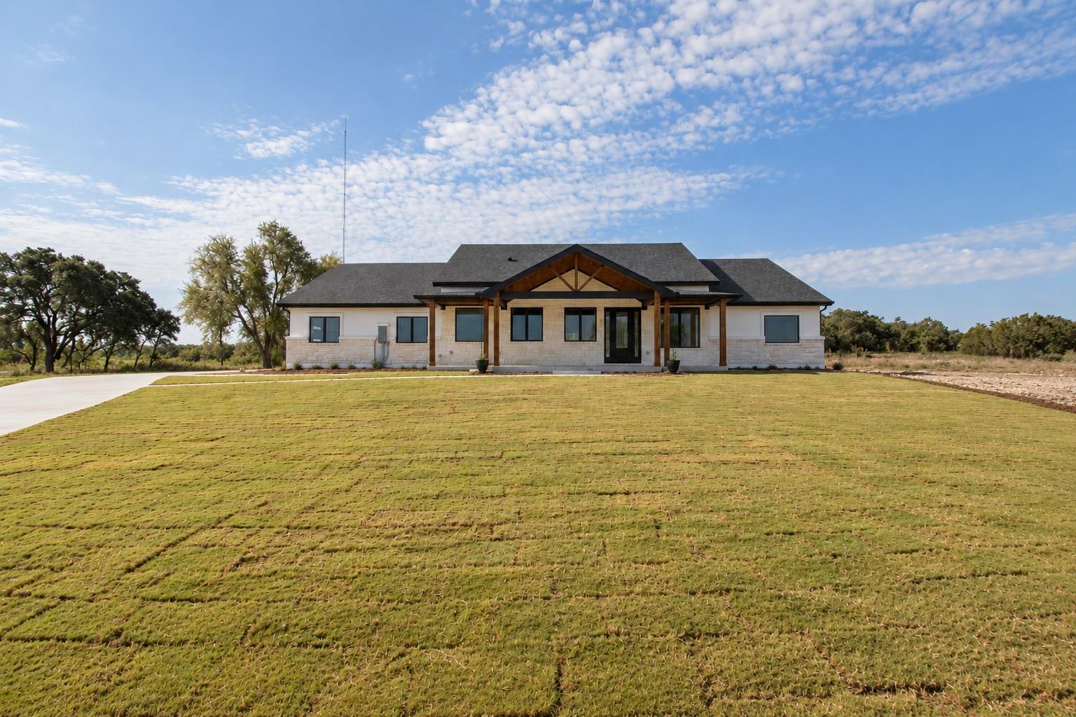 An expansive green lawn leads to a modern one-sto