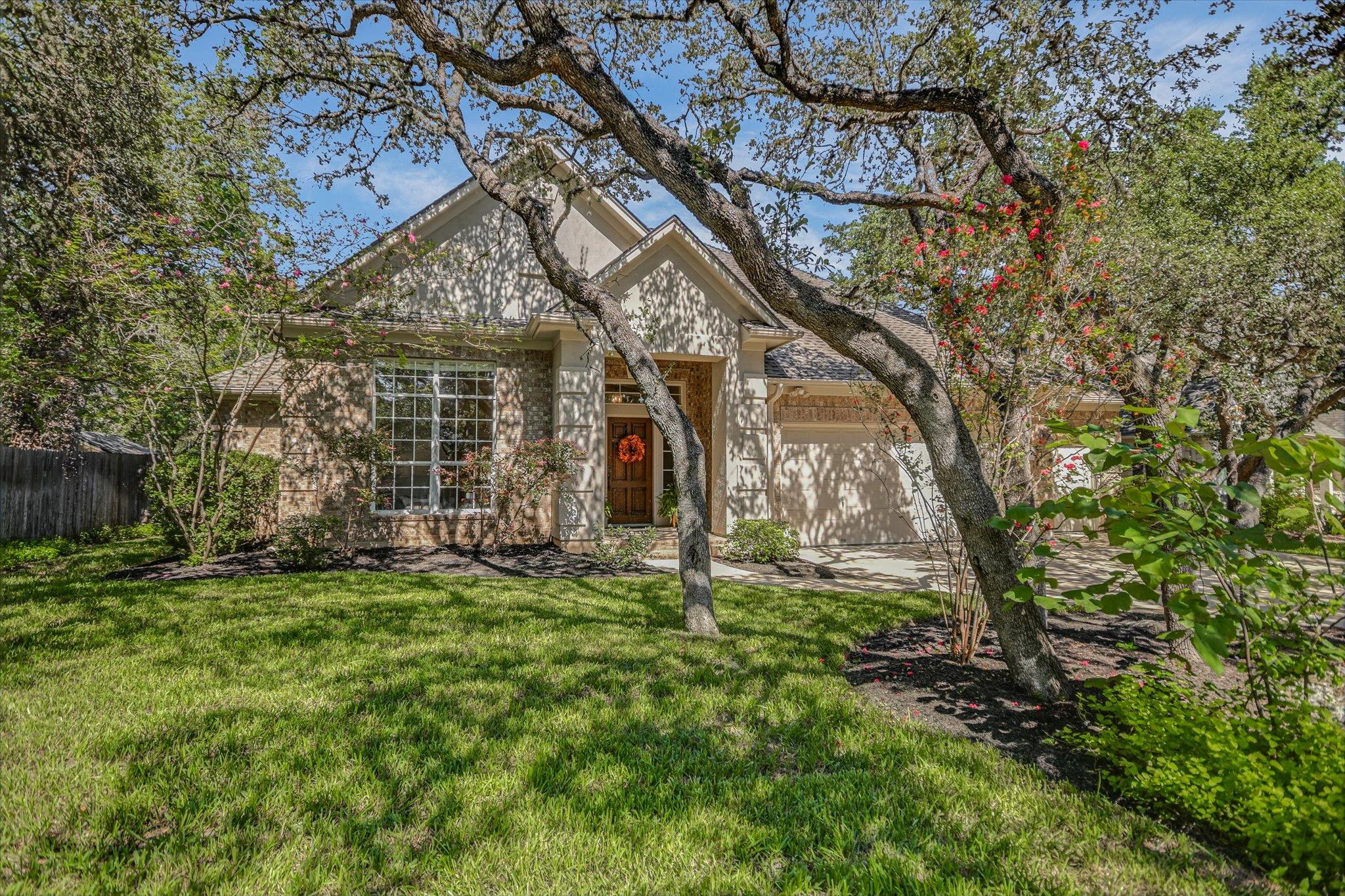 Mature oak trees frame a classic stone and stucco