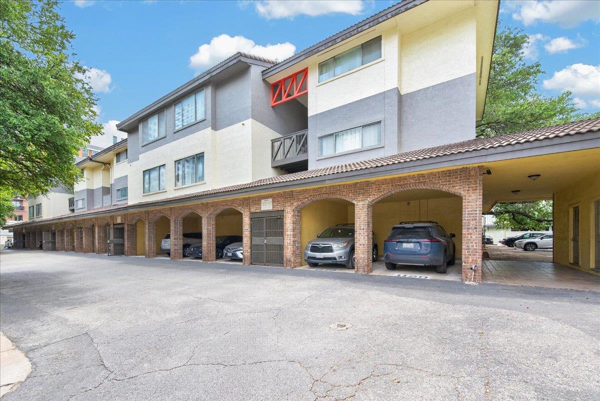 Brick arches frame the covered parking spaces bel