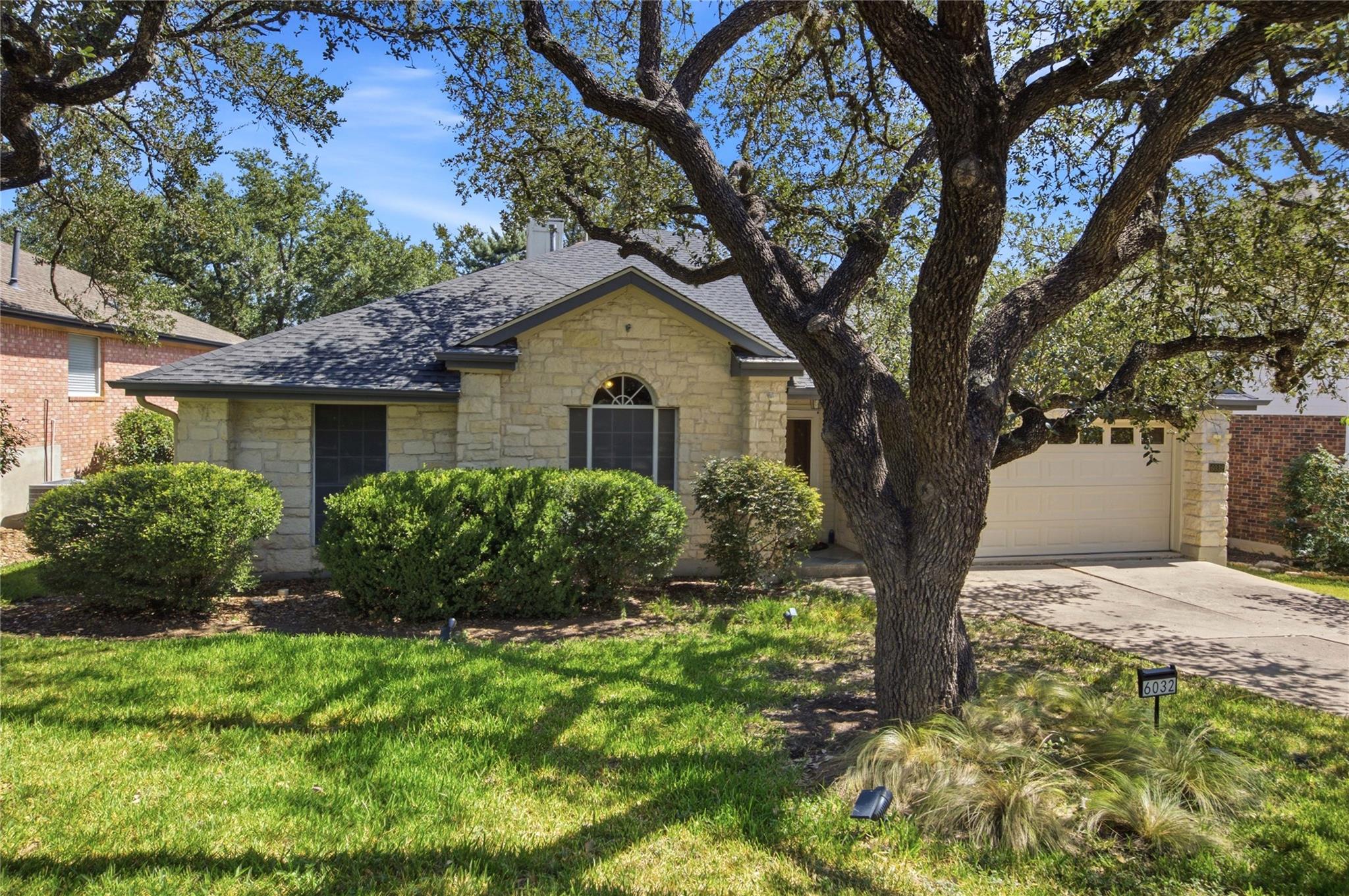 Mature shade trees frame a classic stone exterior