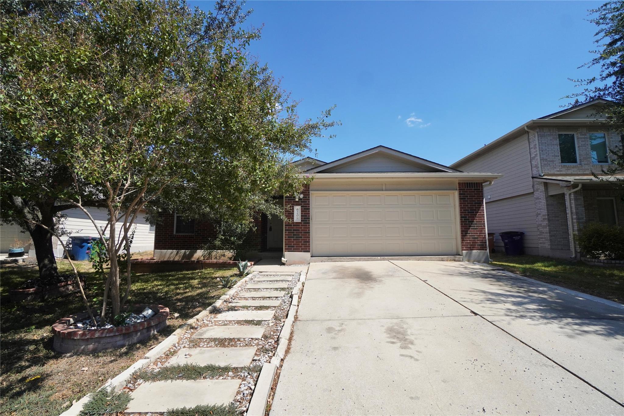 A spacious driveway and neat stone pathway lead t