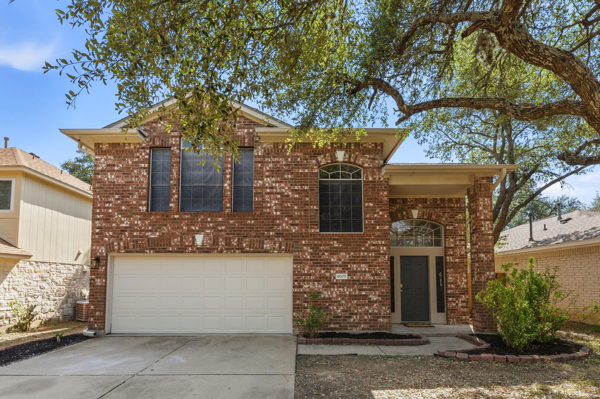 Mature shade trees frame this classic two-story b