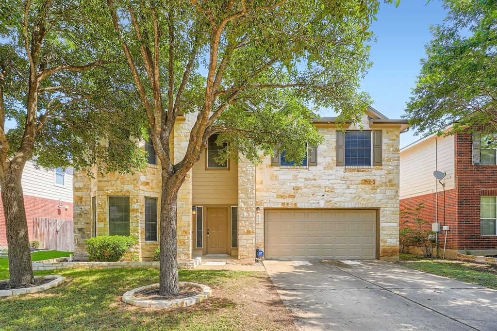 Traditional home featuring stone siding, a garage