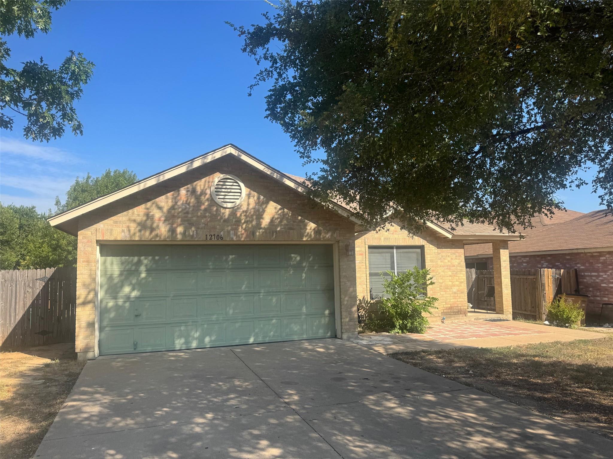 Mature trees shade the concrete driveway and clas