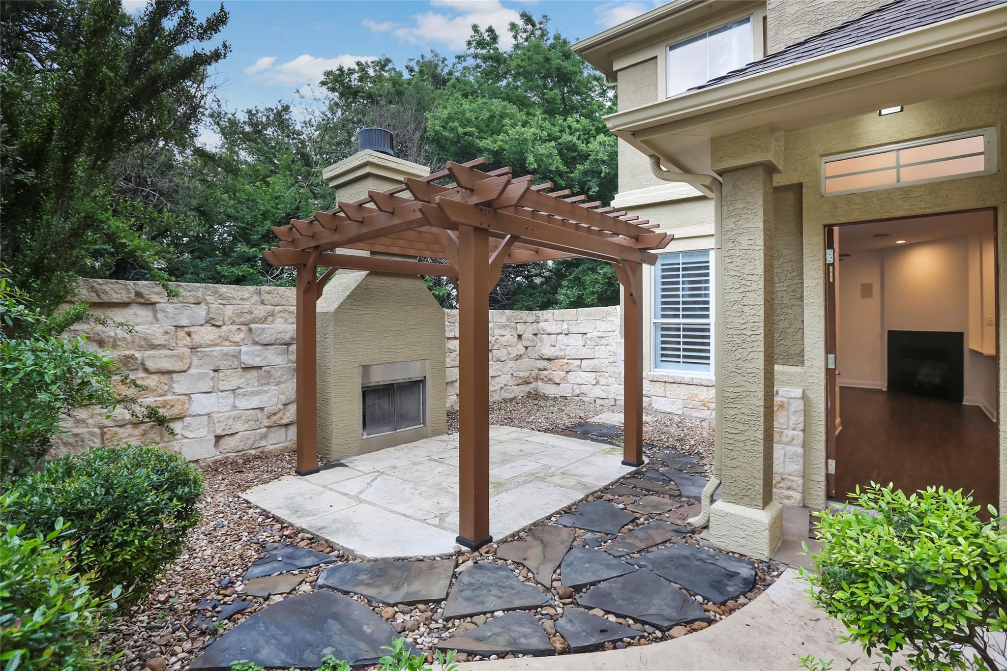 A stone patio with a wood pergola and outdoor fir