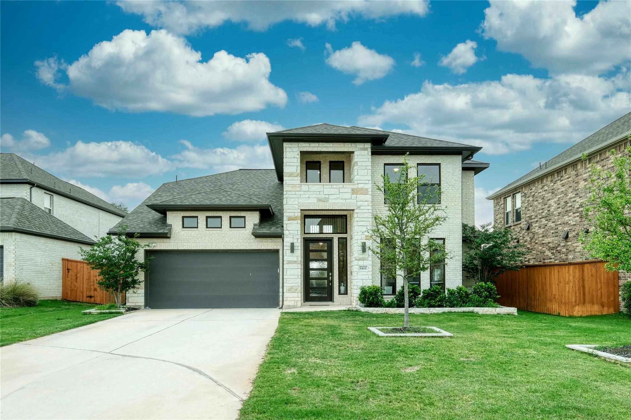 An asphalt driveway leads to a modern brick and s