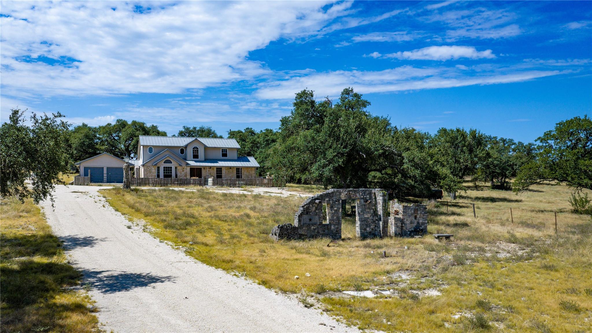 An unpaved driveway leads past rustic stone ruins