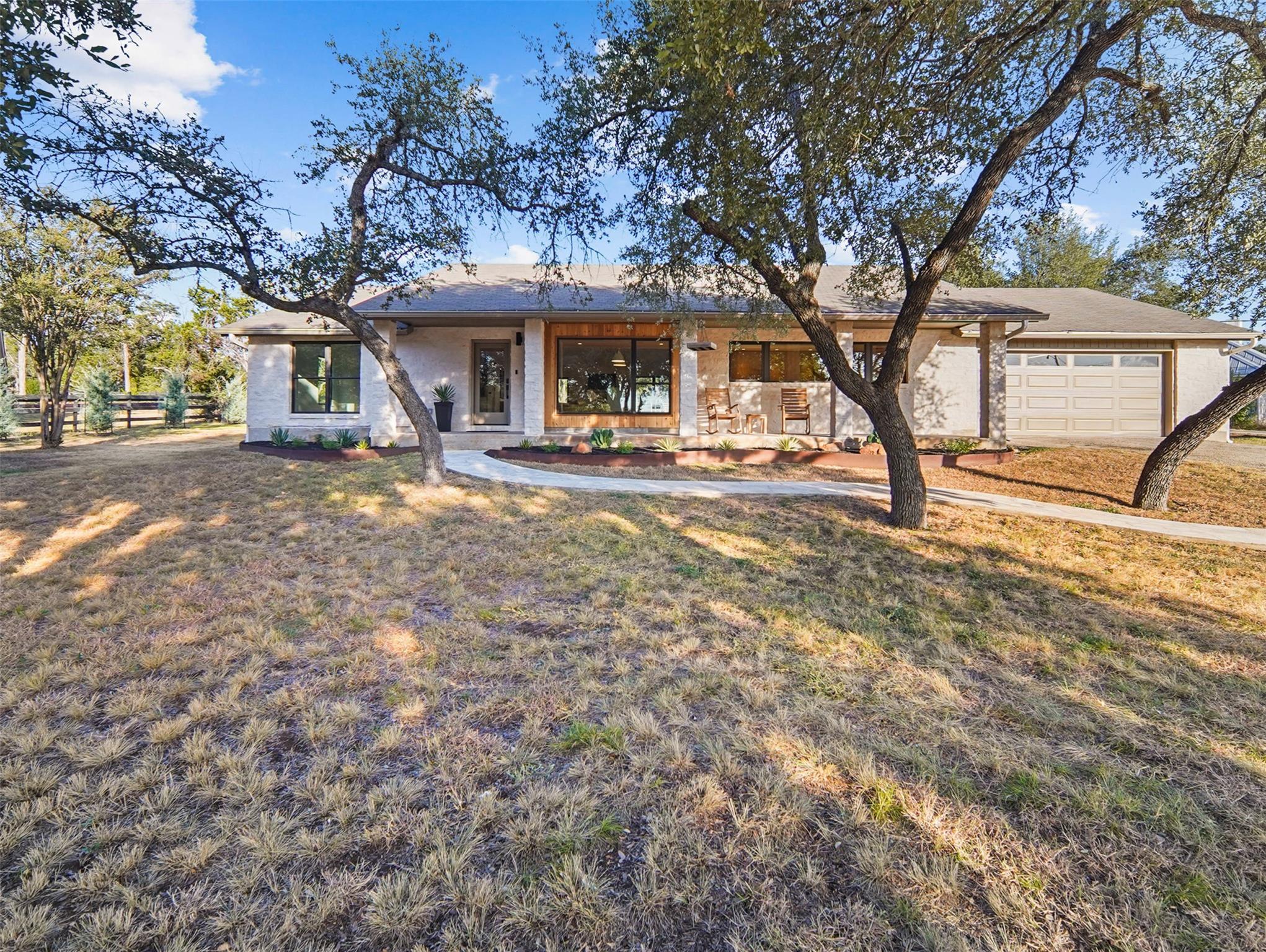 Mature oak trees frame a sprawling single-story f