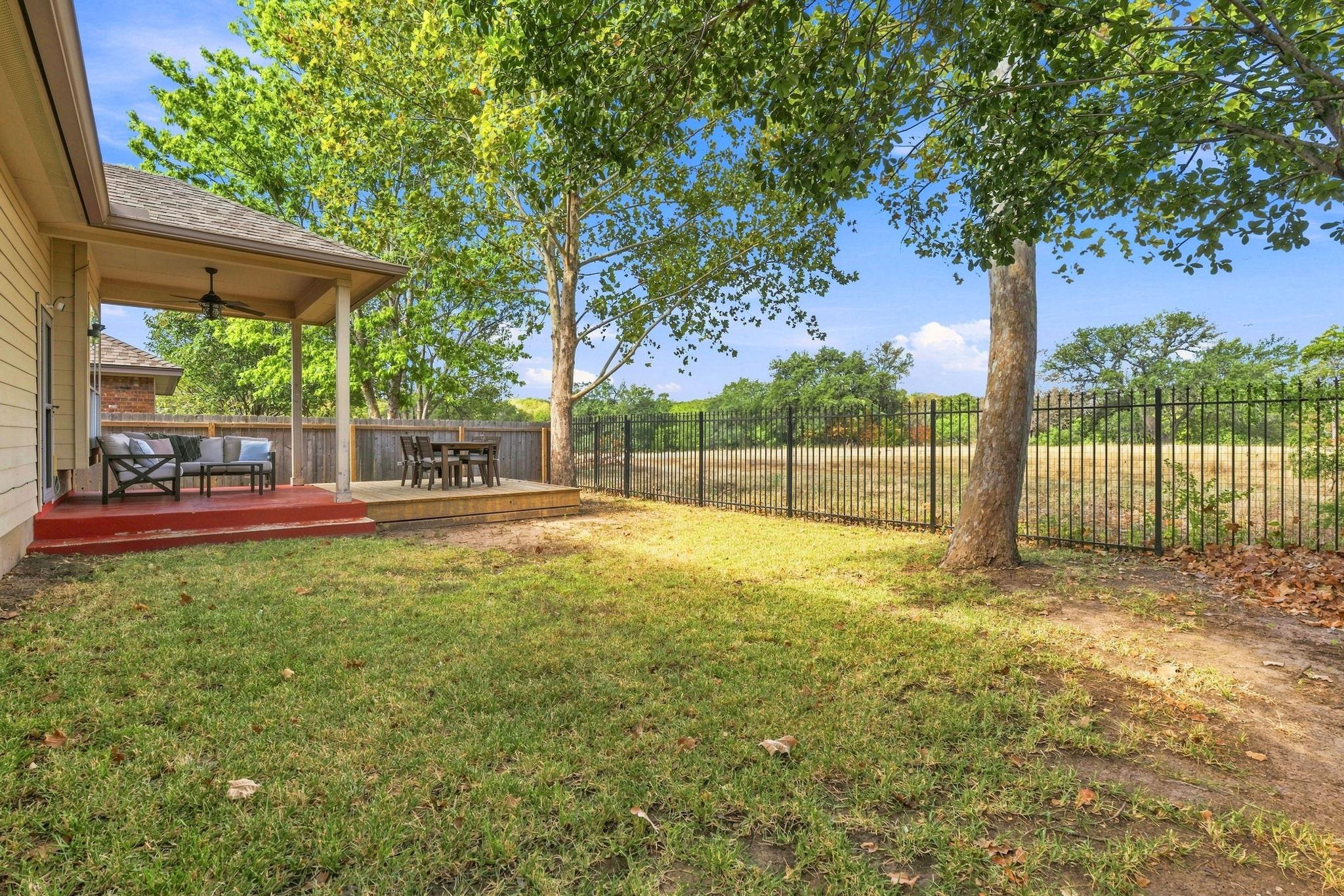 Mature trees shade a grassy lawn bordered by secu